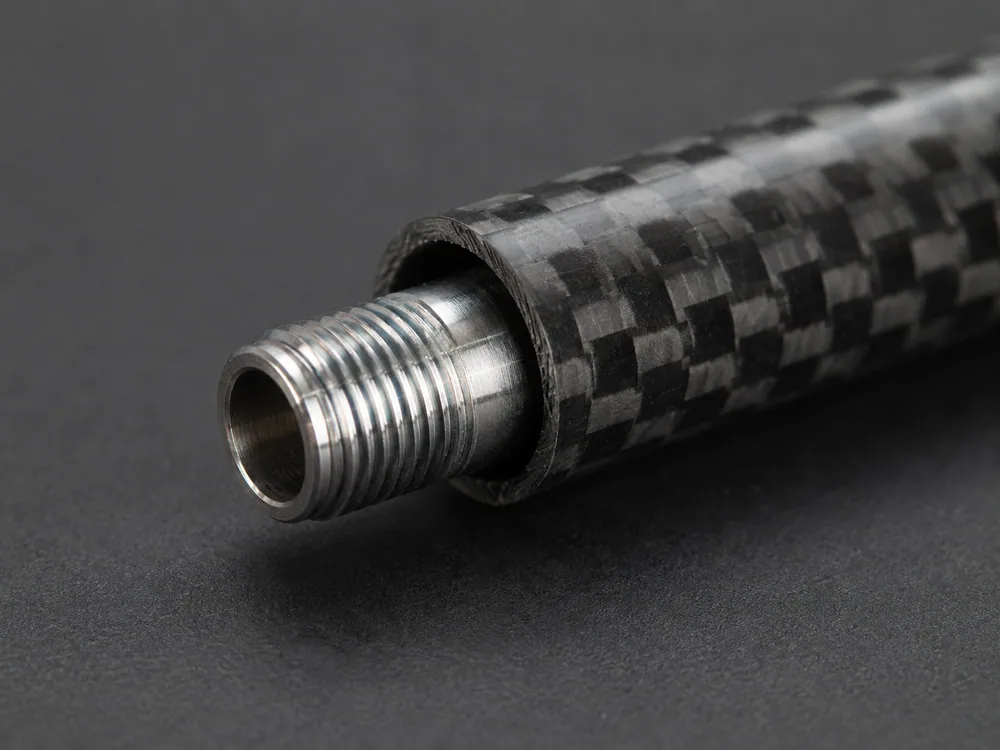 Close-up of a carbon-fibre arrow shaft with a threaded metal insert seated in its open end, on a dark studio background.