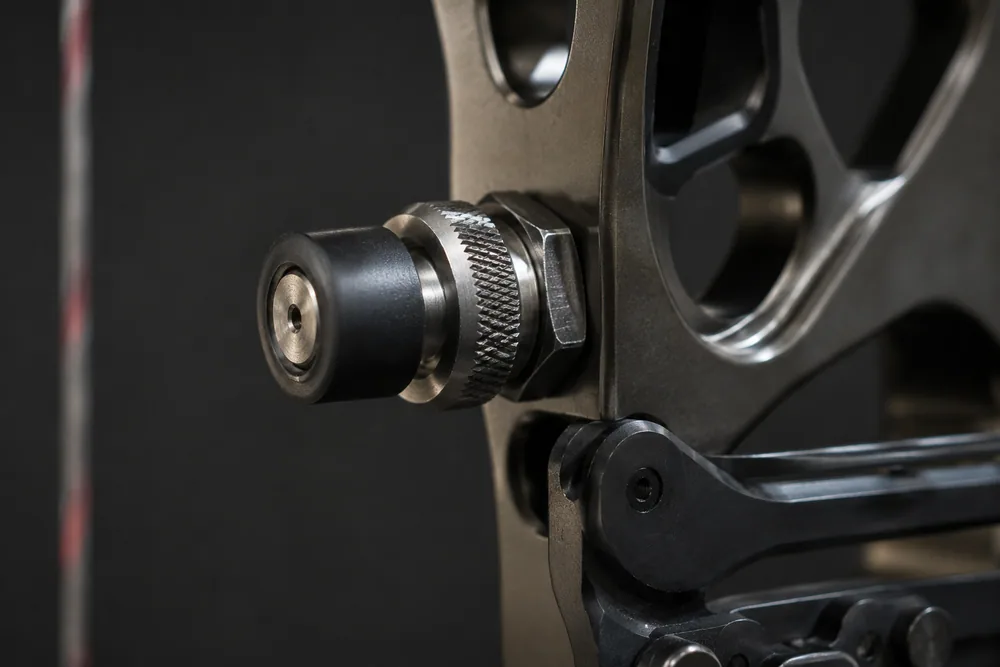 Close-up of a cushion plunger (pressure button) threaded into the side of a bow riser, showing its knurled adjustment barrel.